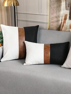 two black and white pillows sitting on top of a gray couch next to a lamp