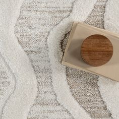 a wooden object sitting on top of a white rug next to a brown and beige box