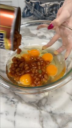 someone is adding eggs to beans in a bowl