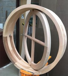 a circular wooden object sitting on top of a table next to a building with windows