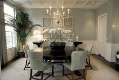 a dining room table with chairs and chandelier in the center, surrounded by pictures on the wall