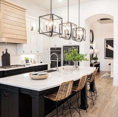 a large kitchen with an island in the middle and lots of lights hanging from the ceiling