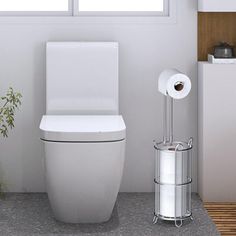 a white toilet sitting in a bathroom next to a trash can and potted plant