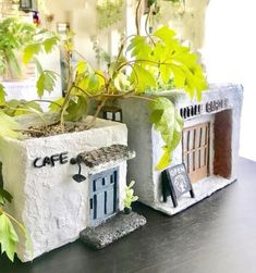 two cement planters sitting on top of a table next to a potted plant