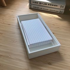 a stack of notebooks sitting on top of a wooden floor next to two books