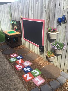 an outdoor area with wooden blocks and numbers on the ground in front of a fence