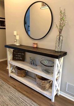 a white shelf with baskets on top and a mirror above it in a living room