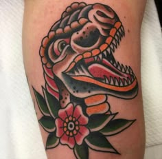 a close up of a tattoo on a person's leg with flowers and an alligator