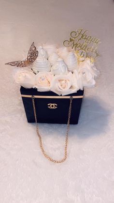 a black box with white flowers and a gold chain on the bottom that says happy mother's day