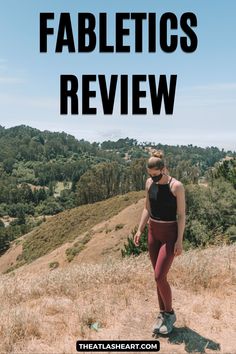 A woman wearing dark red leggings and a black tank top stands on the top of a dry grassy hill and looks down at her feet on a sunny day, with the text overlay, "Fabletics Review." Fabletics Outfits, Clothing Exchange, Orange Theory, Open Back Tank, Green Joggers, Fabletics Leggings