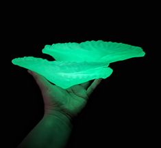 a hand holding two green paper plates in the dark