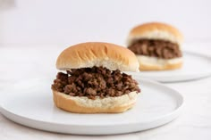 two white plates with sloppy joe sandwiches on them