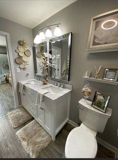 a white toilet sitting next to a sink in a bathroom under a large framed mirror