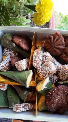 a box filled with assorted pastries sitting on top of a window sill