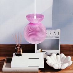 a pink lamp sitting on top of a table next to a laptop computer and other items