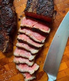 steak sliced up and ready to be served on a cutting board with a knife next to it