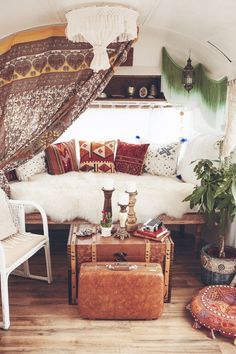 a living room filled with lots of furniture and pillows on top of a hard wood floor