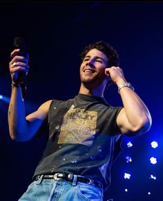 a man holding a microphone up to his ear while standing in front of a crowd