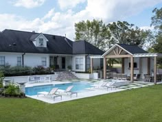 a backyard with a swimming pool and covered patio area next to the home's lawn