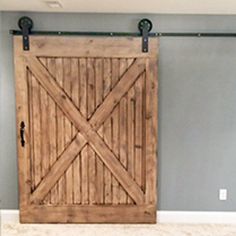 a large wooden sliding door in the corner of a room with gray walls and white carpet