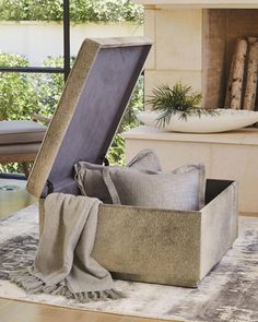 an open suitcase sitting on top of a rug in front of a fire place with pillows