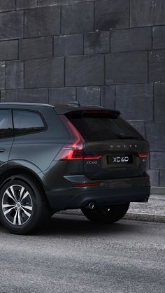 a grey volvo car parked in front of a brick wall