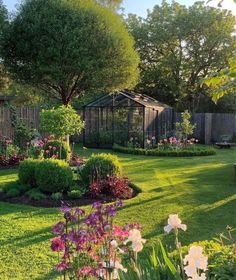 a garden with lots of flowers in the middle of it and a gazebo behind it