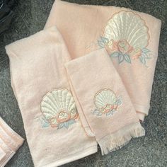 two towels with seashells on them sitting on the ground