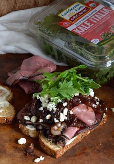 a sandwich with meat, cheese and lettuce sitting on a cutting board next to a container of mayonnaise