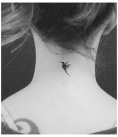 a black and white photo of a small bird tattoo on the back of a woman's neck