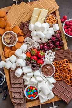 a platter filled with marshmallows, pretzels, fruit and chocolate