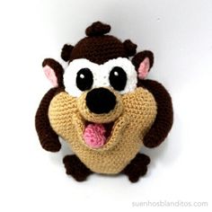 a crocheted stuffed animal with its tongue out and eyes wide open, sitting on a white surface