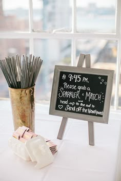 a chalkboard sign next to a vase with sticks in it