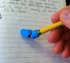 a hand holding a yellow pencil in front of a notebook with writing on the page