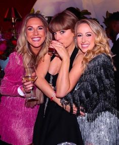 three beautiful women standing next to each other holding wine glasses