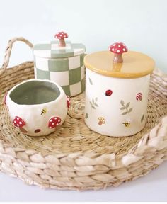 three ceramic containers sitting on top of a wicker tray next to a basket filled with mushrooms