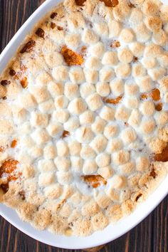 a pie sitting on top of a white plate covered in marshmallows and sauce