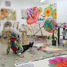 a child sitting on the floor in front of paintings