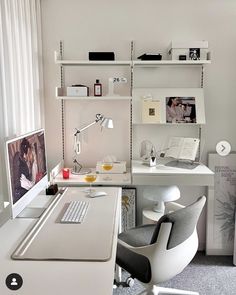 a white desk with a computer on top of it next to a book shelf filled with books