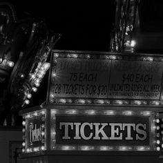 a black and white photo of the front of a ticket booth with lights on it