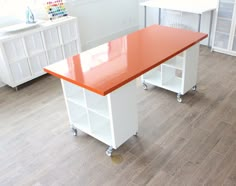 a kitchen with white cabinets and an orange counter top on wheels in front of it