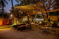 an outdoor restaurant with tables and chairs lit up at night