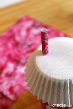 a paper cupcake with a candle sticking out of it's top on a table