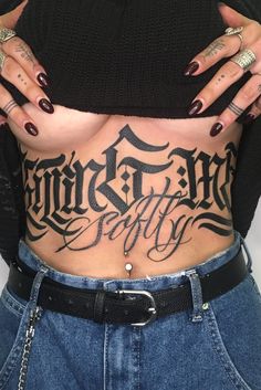 a woman with tattoos on her stomach holding onto the back of her body and wearing jeans