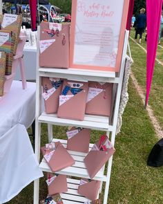 pink and white display at an outdoor event with lots of papers on the top shelf