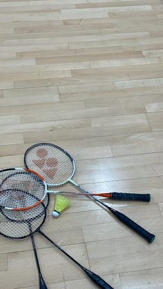 four badminton rackets laying on the floor next to each other