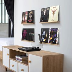 a record player sitting on top of a wooden table next to a white wall with pictures above it