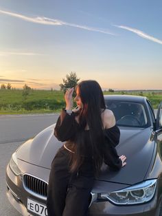 a woman sitting on the hood of a car