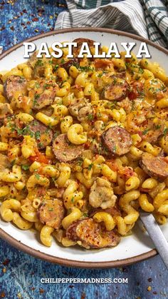 pasta with sausage and tomato sauce in a white bowl on top of a blue table cloth