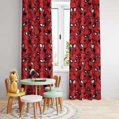 a spiderman themed room with red curtains and table, chairs, and teddy bear